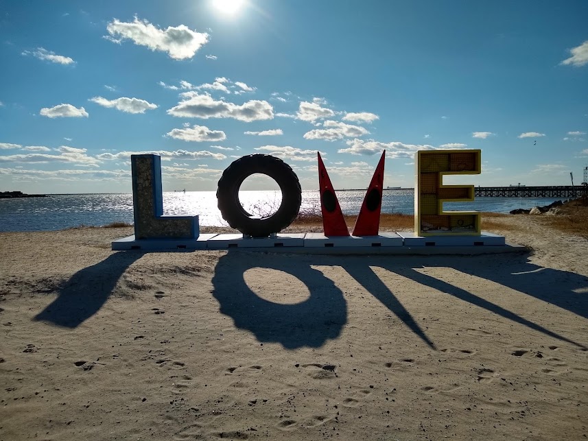 "love" sign with the V made out of kayaks with water in background and sand in the foreground