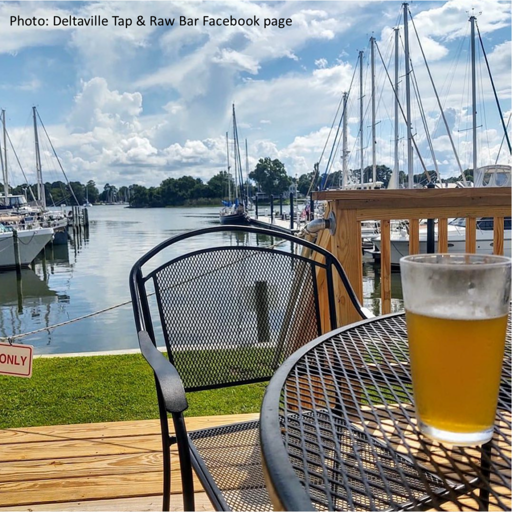 a pint of beer sitting on a table in the sunshine, overlooking a marina with sailboats