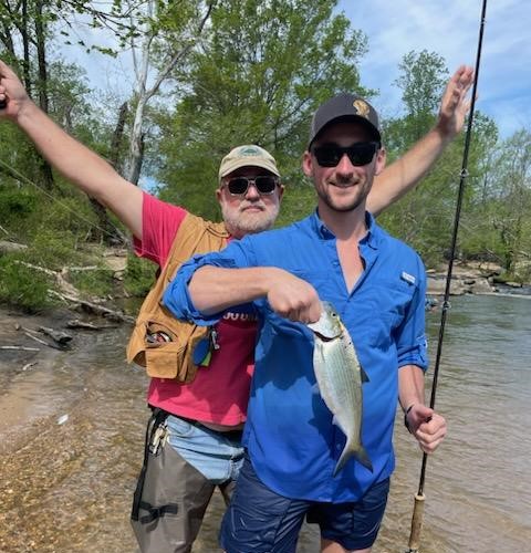 Two anglers posing with a freshly caught Hickory shad on the banks of the Rappahannock River during the spring shad run